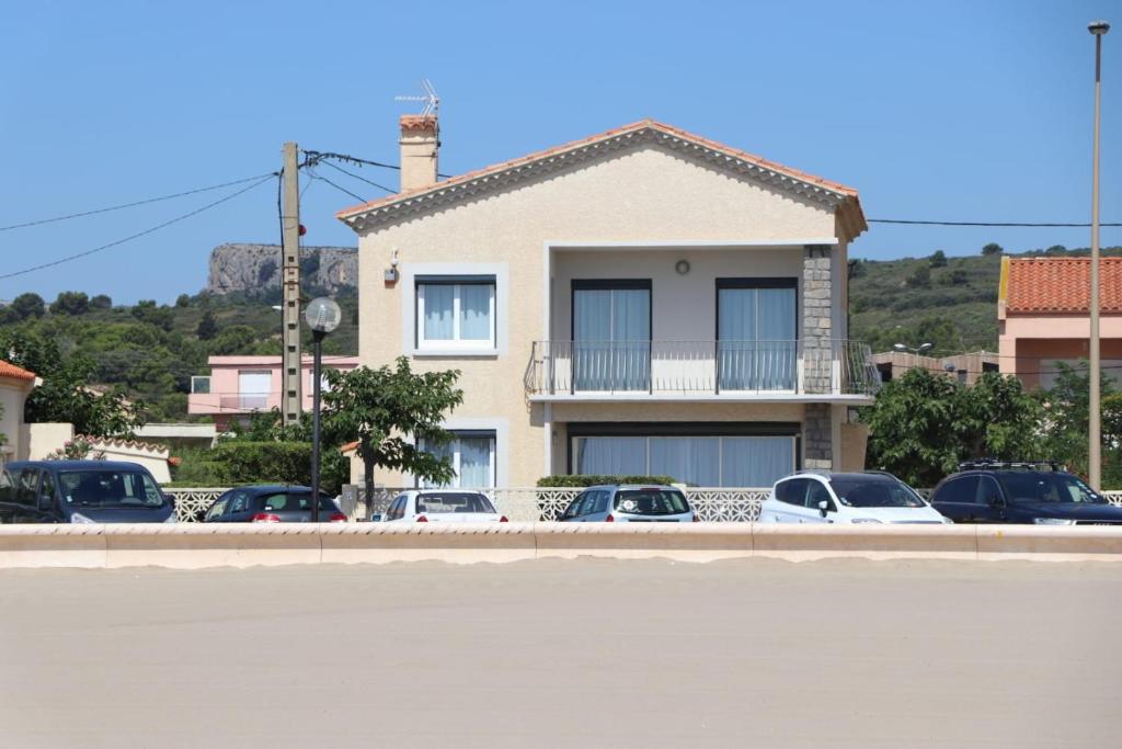 a building with cars parked in a parking lot at Belle maison, en bord de plage in Narbonne-Plage