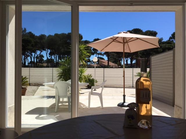 eine Terrasse mit einem Sonnenschirm, einem Tisch und Stühlen in der Unterkunft Appartements Les Pesquiers Hyères Plage in Hyères