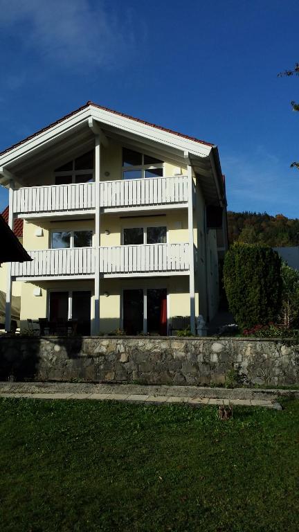 een groot wit huis met een veranda en een balkon bij Ferienwohnung Valentin in Hohenpeißenberg