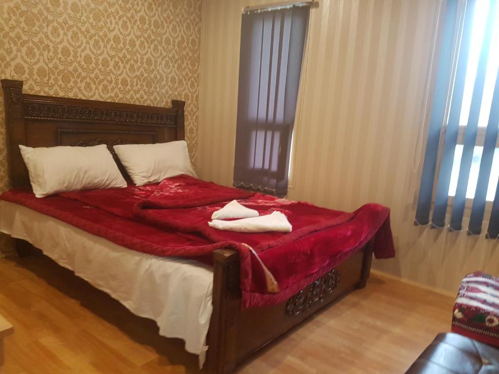 ein Bett mit einer roten Decke und zwei Handtüchern darauf in der Unterkunft Khunjerab Hotel Sost in Gircha