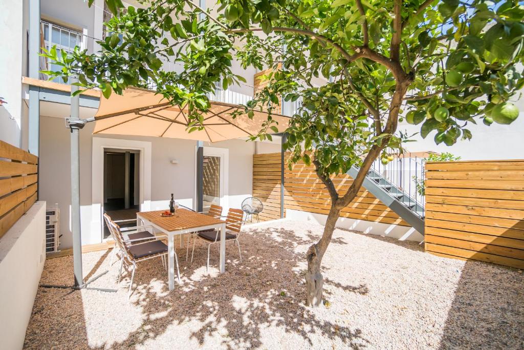 リスボンにあるLemon Tree Garden 3bedroom Apartmentの木の下にテーブルと椅子のあるパティオ