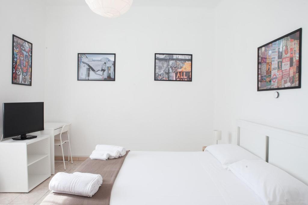 a white bedroom with a bed and a desk with a tv at Residenza Cleopatra 1 in Ancona