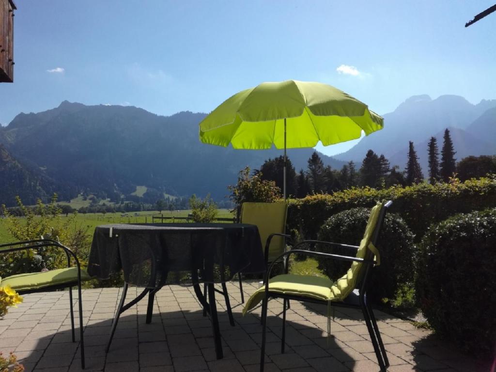 een tafel en stoelen met een groene parasol bij Lizzi Mountain Apartments in Schwangau