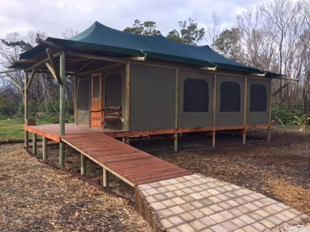 a green cabin with a deck and a blue roof at Hillcrest Lodge Tents - Nelanga in Plettenberg Bay
