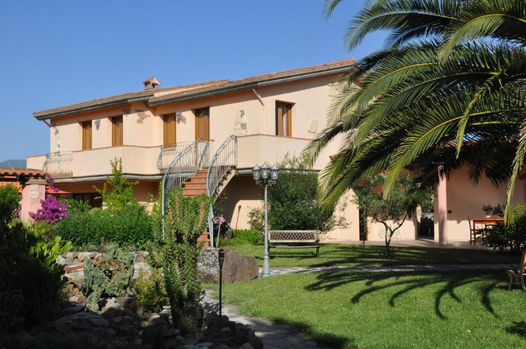 a house with a palm tree in front of it at Agriturismo S´Aranada in Marrùbiu