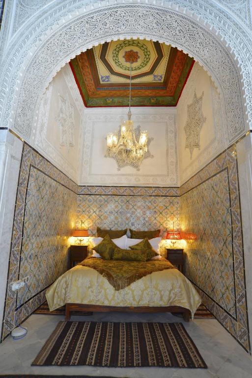 a bedroom with a large bed with a chandelier at Palais Bayram in Tunis