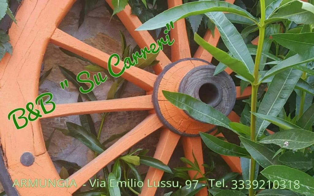 una rueda de madera pegada a una valla con hojas en Su Carreri, en Armungia