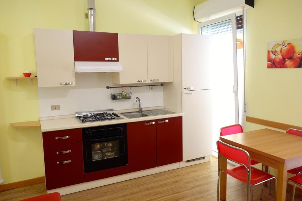 een keuken met rode kasten en een houten tafel met een eetkamer bij Appartamento Holiday Rimini 100mt dal mare in Rimini