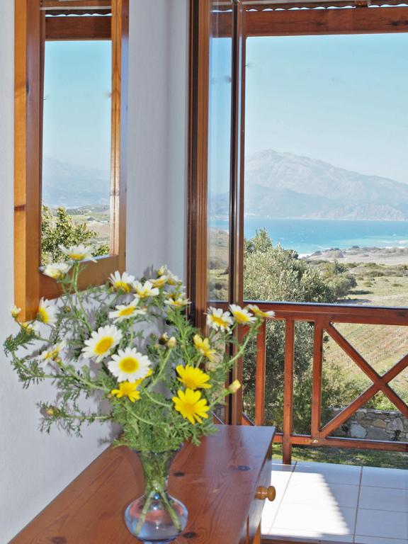 a vase filled with yellow flowers on a table in front of windows at Irene Komos in Pitsidia