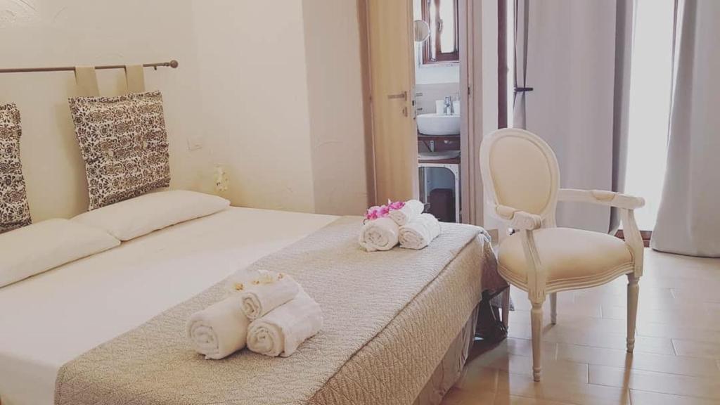 una camera con letto, sedia e asciugamani di Perla Del Borgo Bed and Breakfast a Santa Caterina dello Ionio