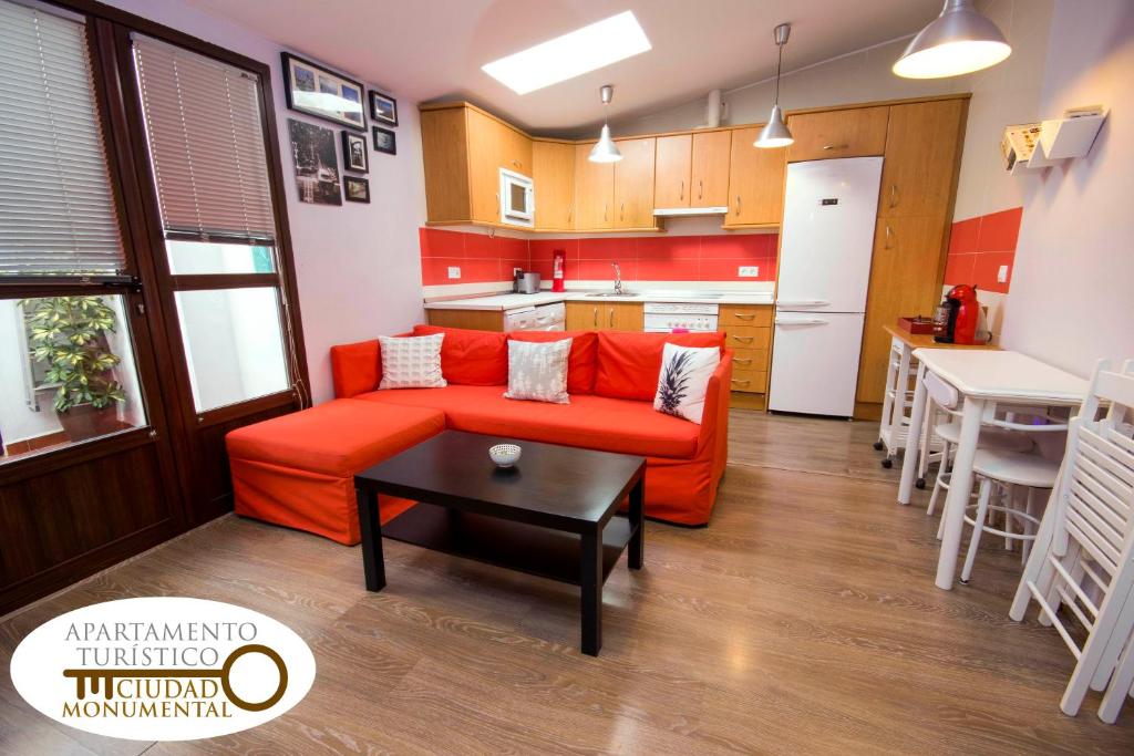 a living room with a red couch and a kitchen at Apartamento Ciudad Monumental in Cáceres