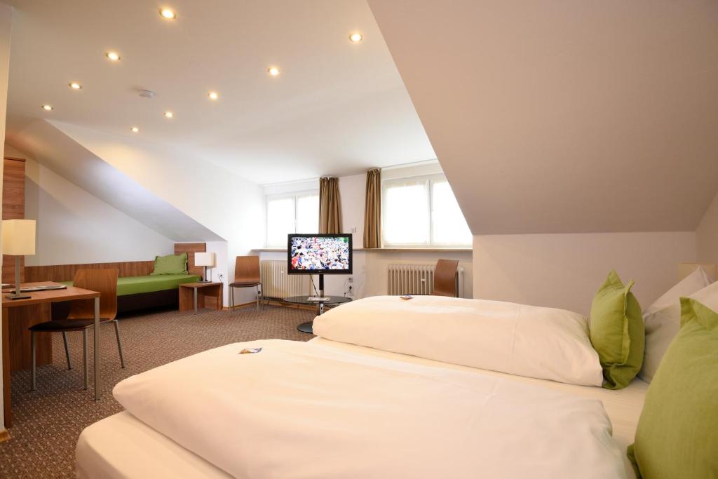 a hotel room with two beds and a television at Hotel Hecht Garni in Ingolstadt