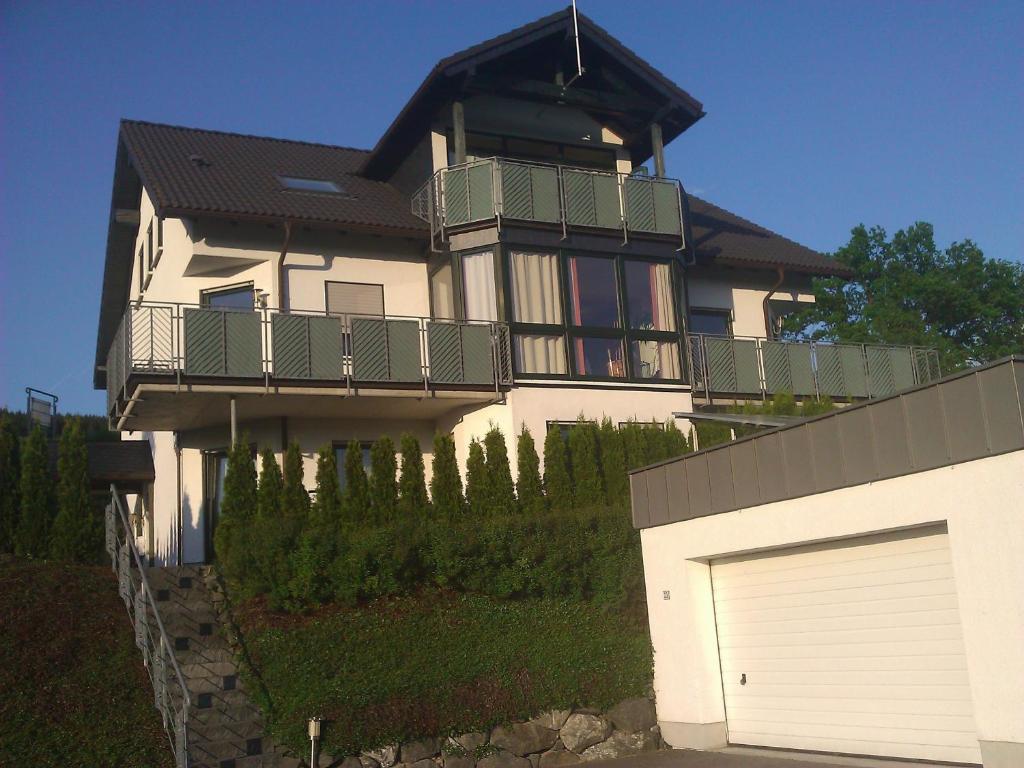 a large house with a balcony and a garage at Ferienwohnung Moos-Hochsauerland in Wiemeringhausen