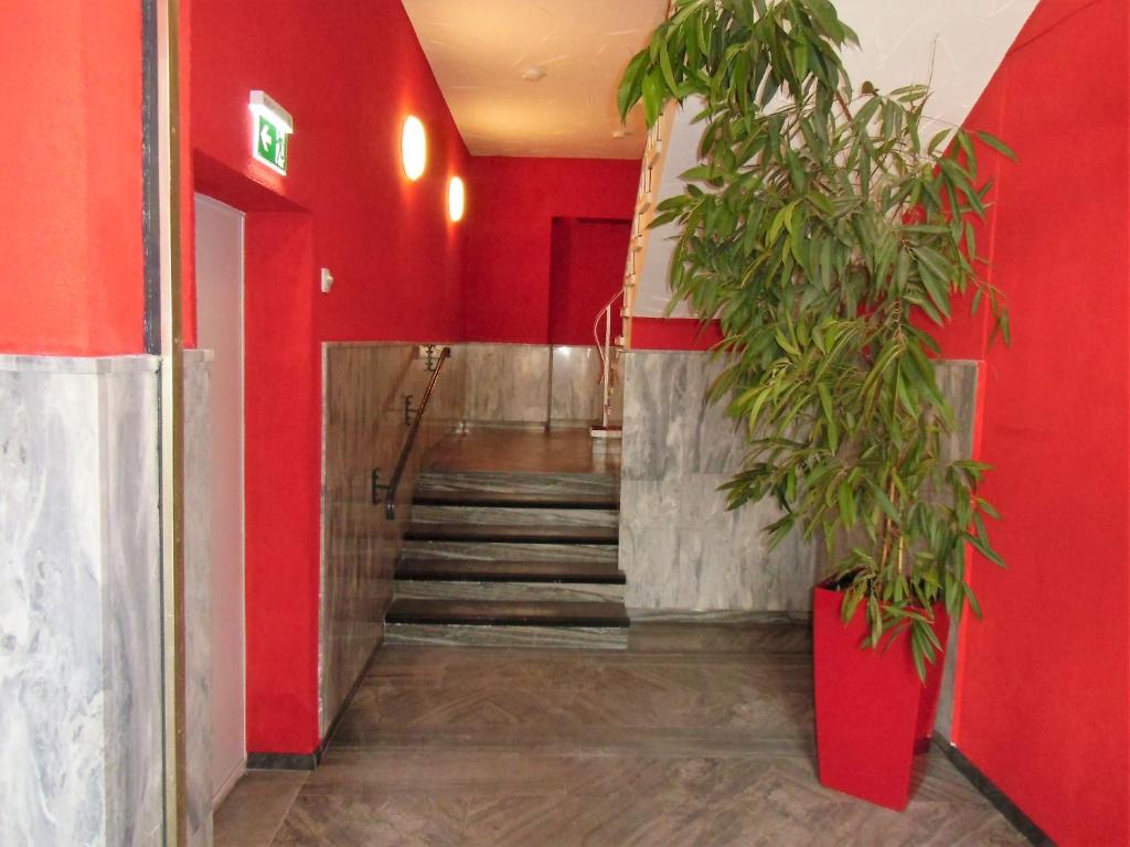 un pasillo con paredes rojas y una escalera con una planta en Ricks City Hotel en Tréveris