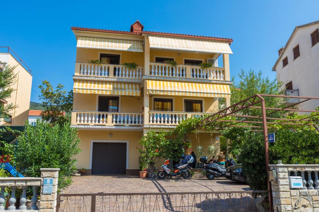 a yellow building with a balcony on top of it at Apartman Laura in Selce