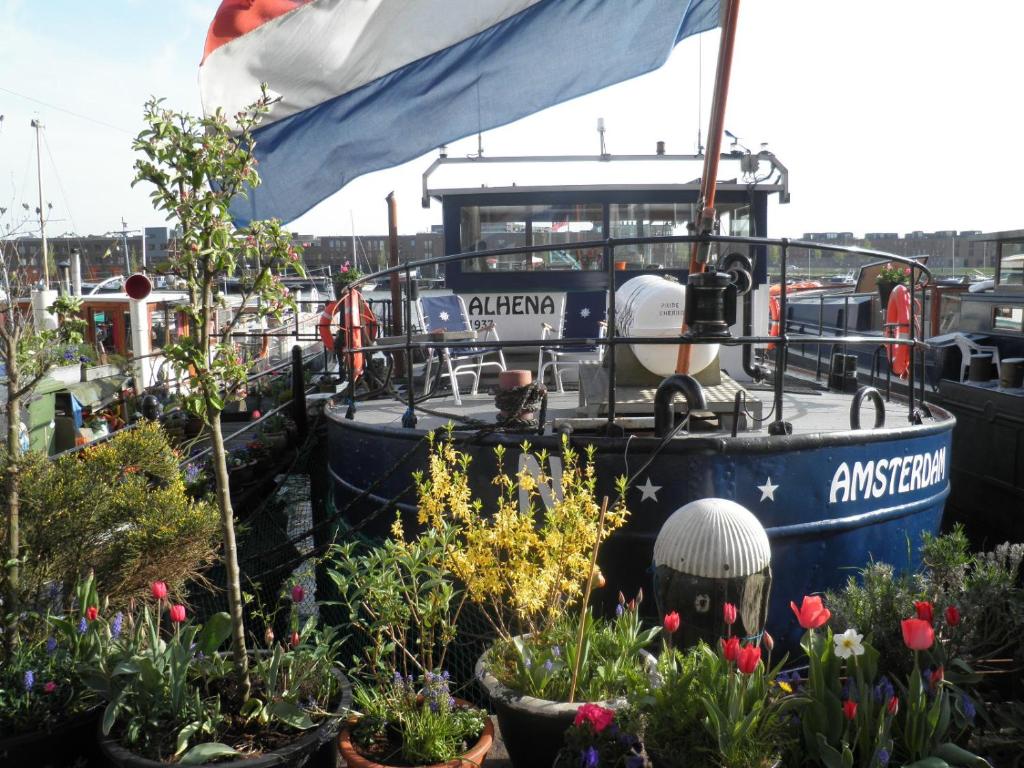 a boat docked in a marina with flowers and plants at Boat & Breakfast Alhena in Amsterdam