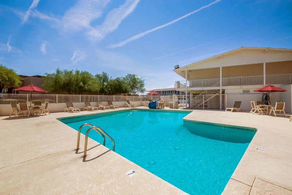 a swimming pool at a resort with chairs and umbrellas at Motel 6-Youngtown, AZ - Phoenix - Sun City in Youngtown
