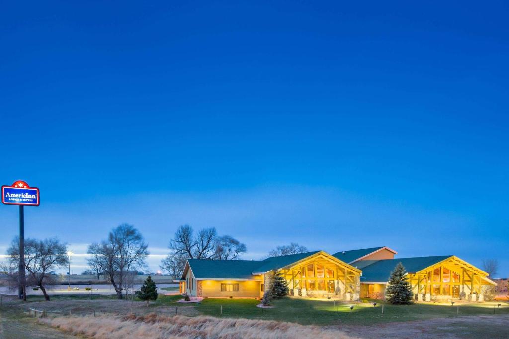 une maison la nuit avec un panneau devant elle dans l'établissement AmericInn by Wyndham Chamberlain Conference Center, à Chamberlain