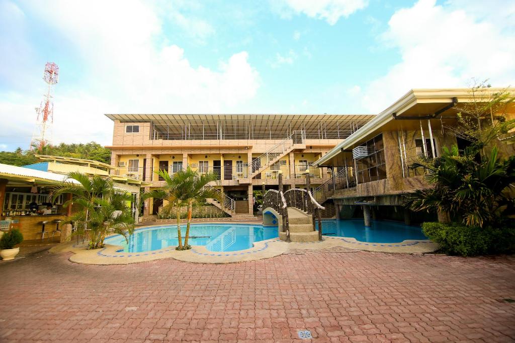 a large building with a swimming pool in front of it at GingGing Hotel And Resort in Oslob