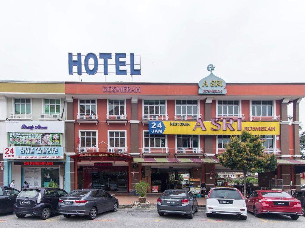 a hotel with cars parked in a parking lot at Hotel Rosmerah in Ayer Keroh