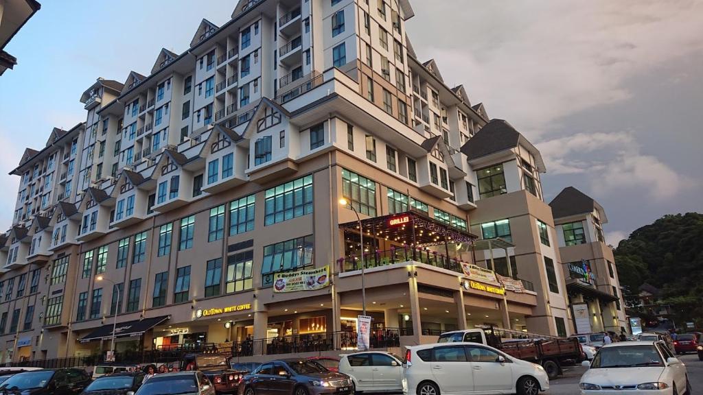 un gran edificio con coches estacionados en un estacionamiento en ATS Cameron Hotel & Apartments en Cameron Highlands