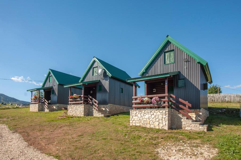 zwei Häuser mit grünen Dächern auf einem Feld in der Unterkunft Woodland ABC in Žabljak