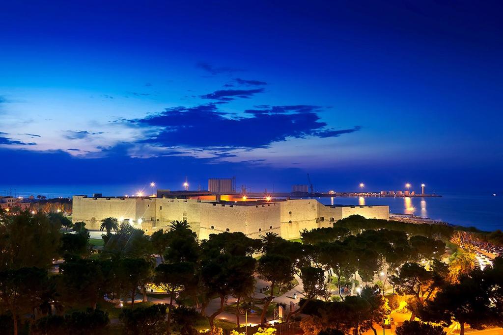 un grande castello di notte con una città di Casa Vacanze Disfida di BARLETTA suite a Barletta