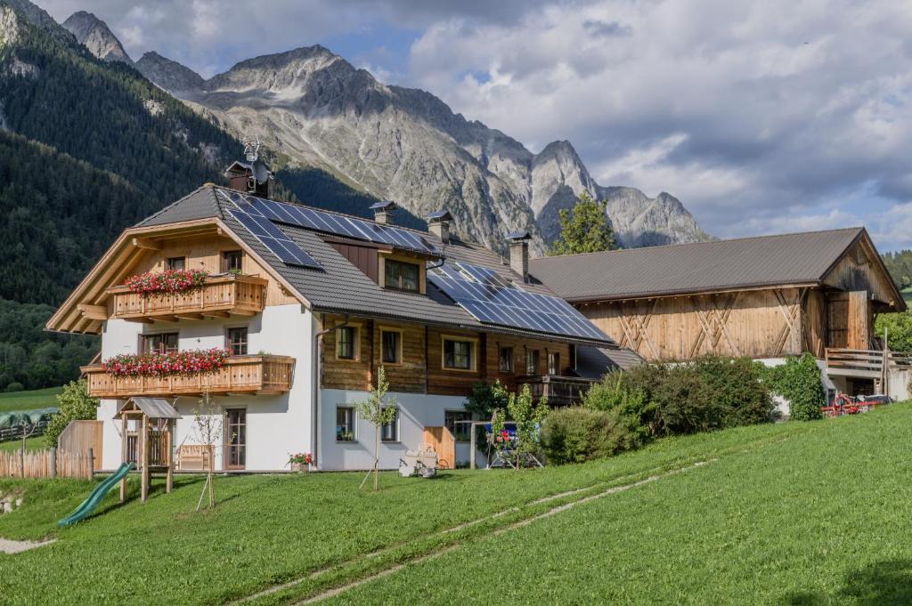 a house with solar panels on it in front of mountains at Unterreinischhof in Anterselva di Mezzo