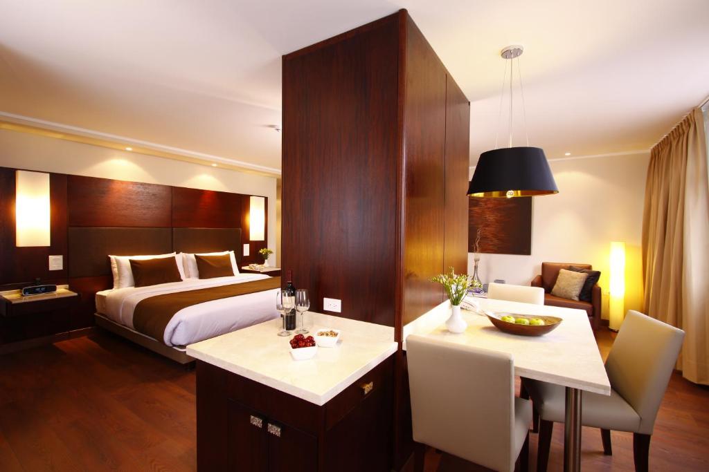 Hotel Reina Isabel في كيتو: غرفة فندقية بسرير وطاولة وكراسي