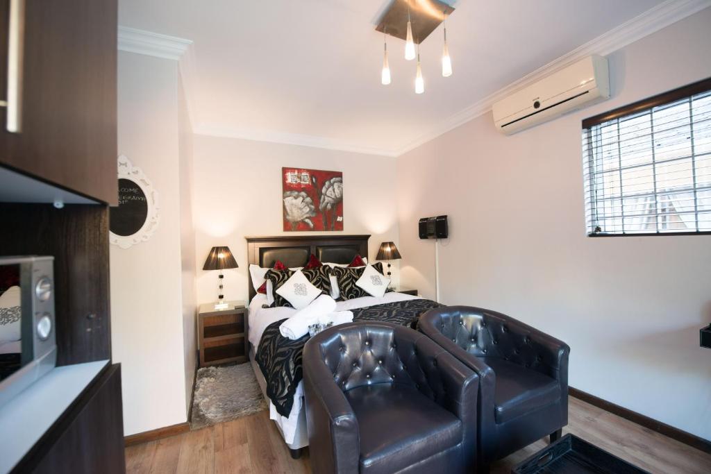 a bedroom with a bed and a leather couch at Keiskama B & B in Port Elizabeth