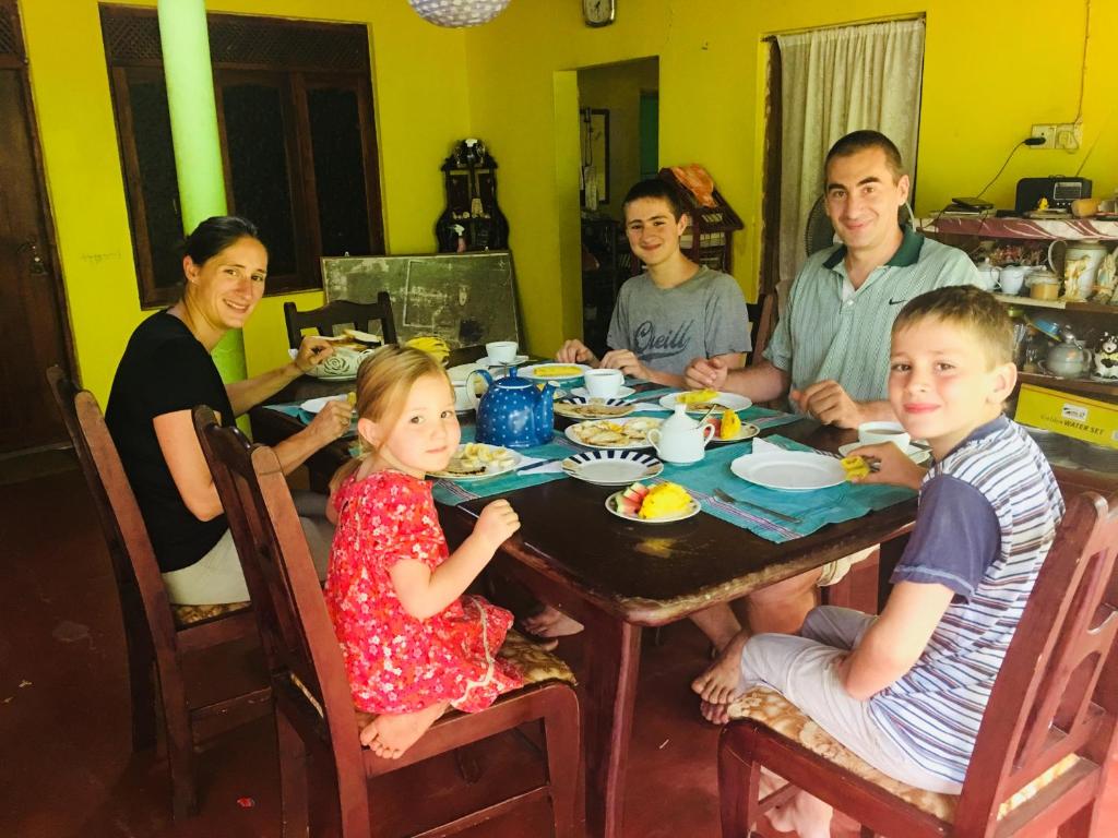 a family sitting at a table eating food at The Nilmini Lodge in Sigiriya