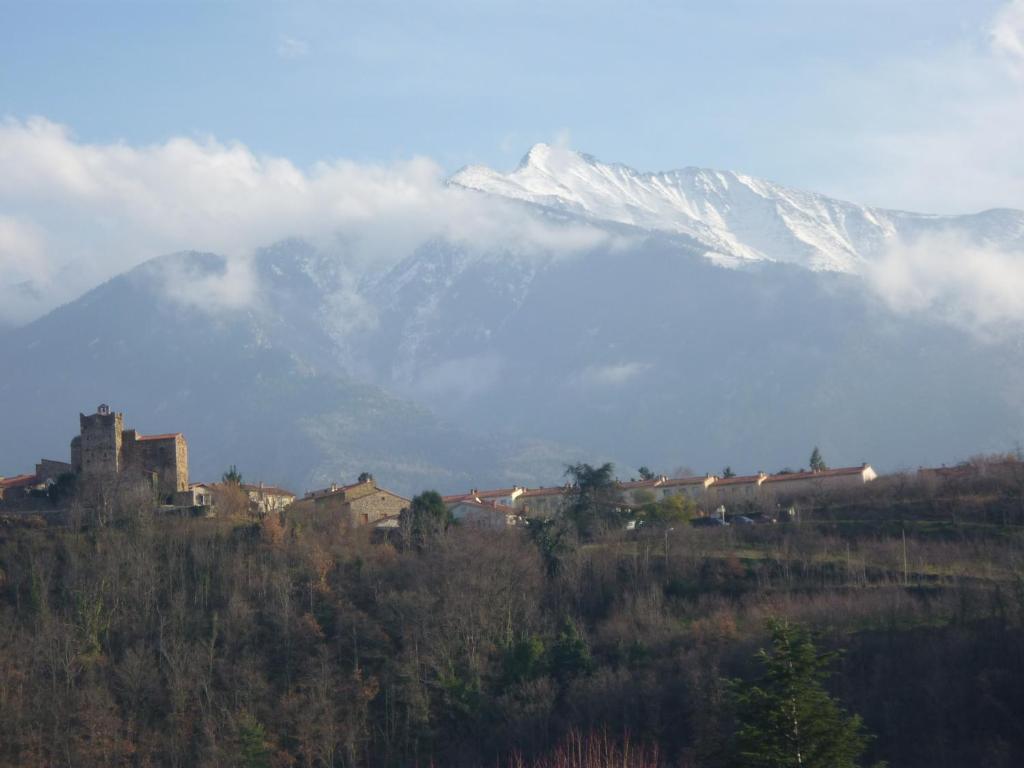 a snow covered mountain in the distance with a town and a train at Chez Vivi in Ria