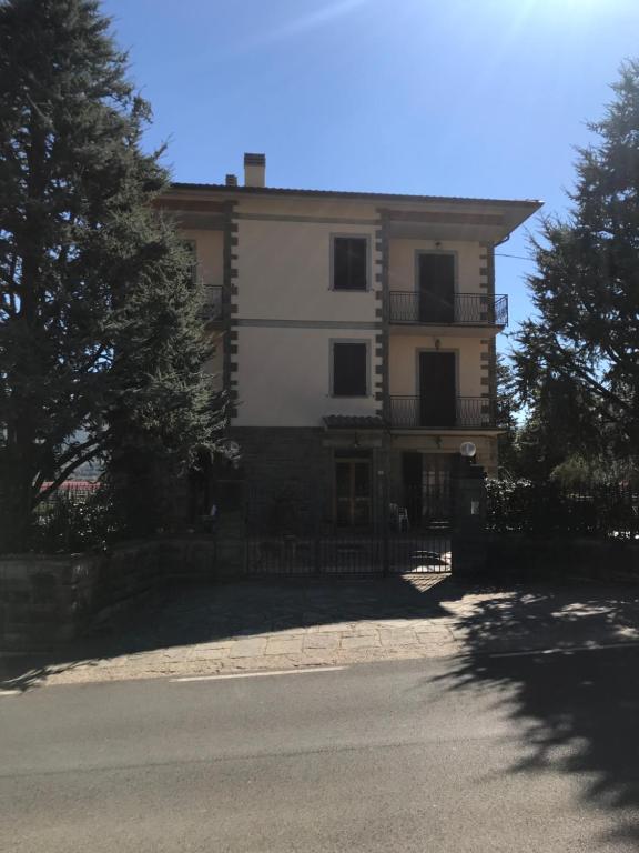 un grand bâtiment blanc avec des arbres devant lui dans l'établissement Casa FONTESECCA, à Castiglion Fiorentino
