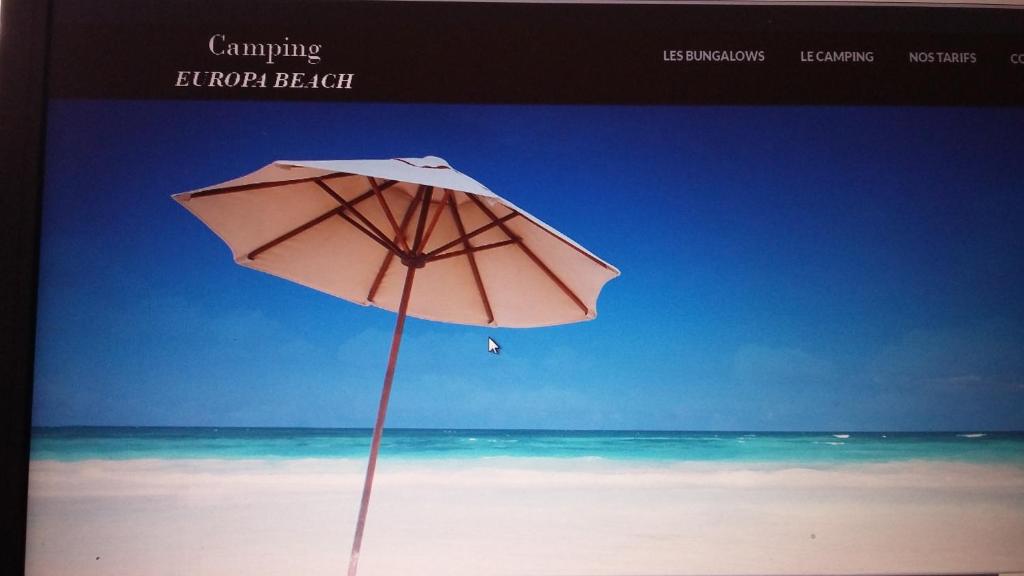 - un parasol rose assis sur une plage donnant sur l'océan dans l'établissement Camping Europa Beach, à Castellare-di-Casinca