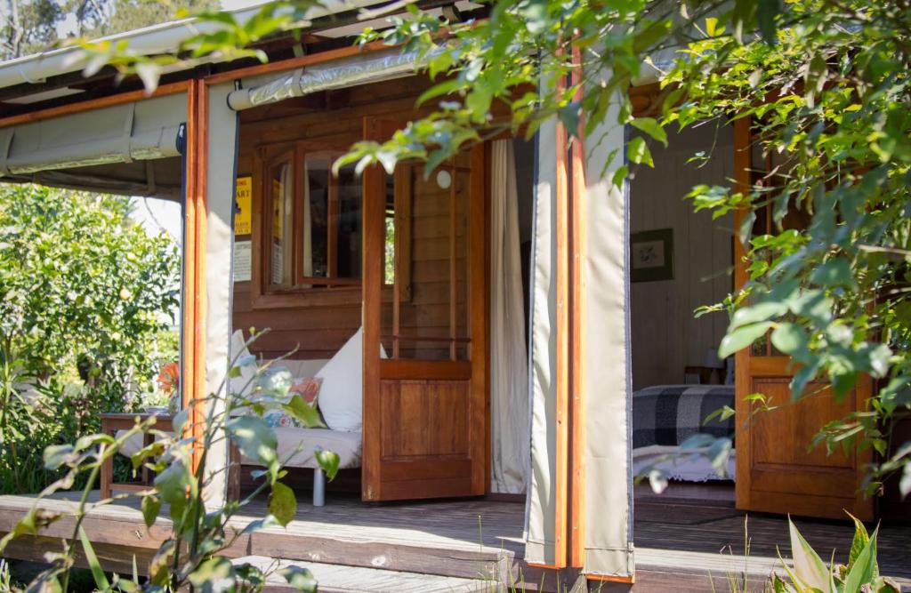 une terrasse couverte d'une maison avec une porte en bois dans l'établissement Pear Tree Cottage, à Stormsrivier