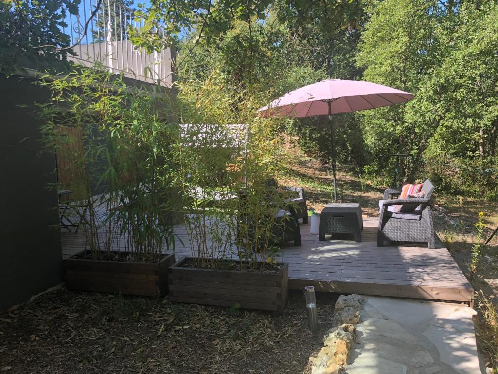 a patio with a table and an umbrella and chairs at La Chênaie in Mouans-Sartoux