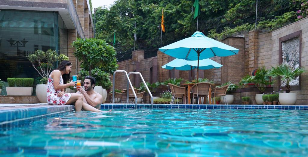 a man and a woman sitting next to a swimming pool at Jaypee Siddharth in New Delhi