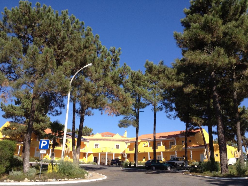 a parking lot in front of a yellow building with trees at Hotel Rural Monte da Leziria in Santo André
