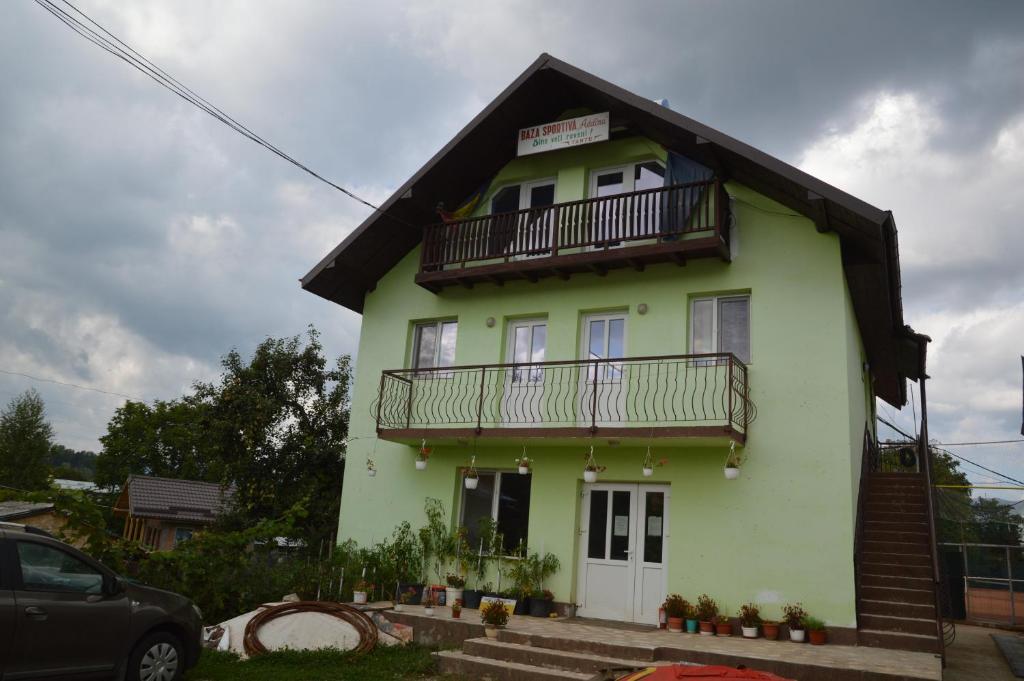 a yellow and green house with a balcony at Baza Sportiva Adelina in Cîmpulung