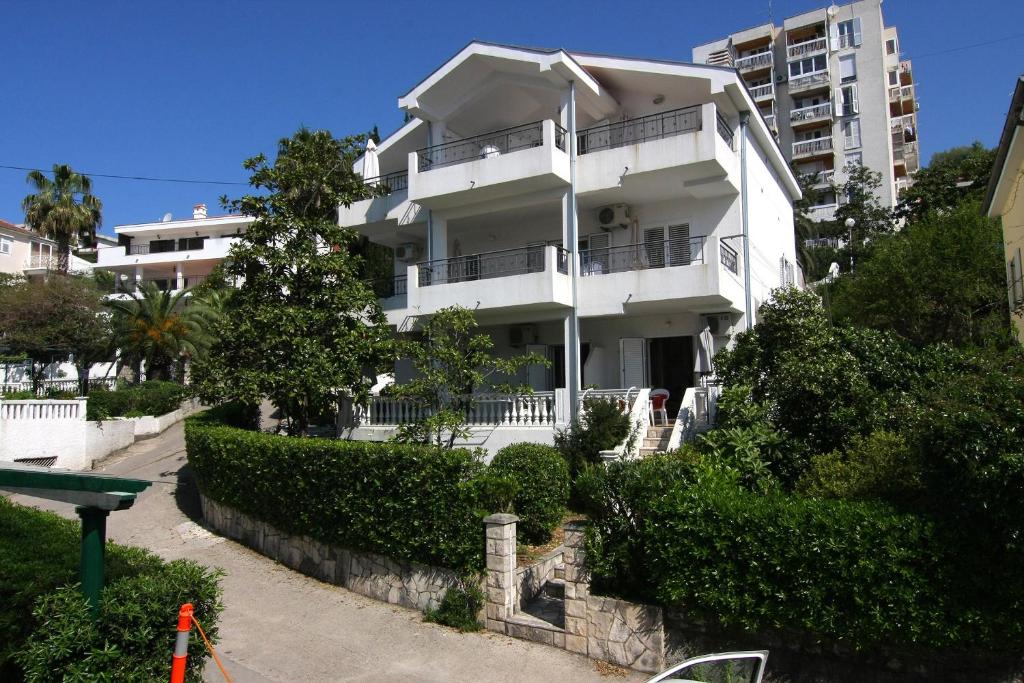 ein weißes Apartmenthaus mit einem Baum davor in der Unterkunft Nikic Apartments in Herceg-Novi