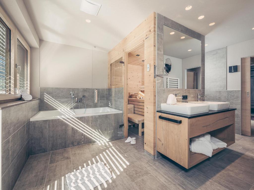 a bathroom with a tub and a sink and a mirror at Postresidenz in Mayrhofen