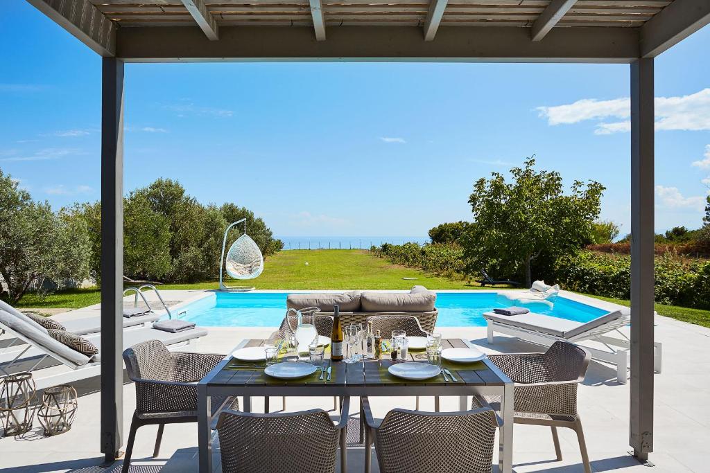 a patio with a table and chairs and a pool at Art Villas (Piano & Violin) in Skala Kefalonias
