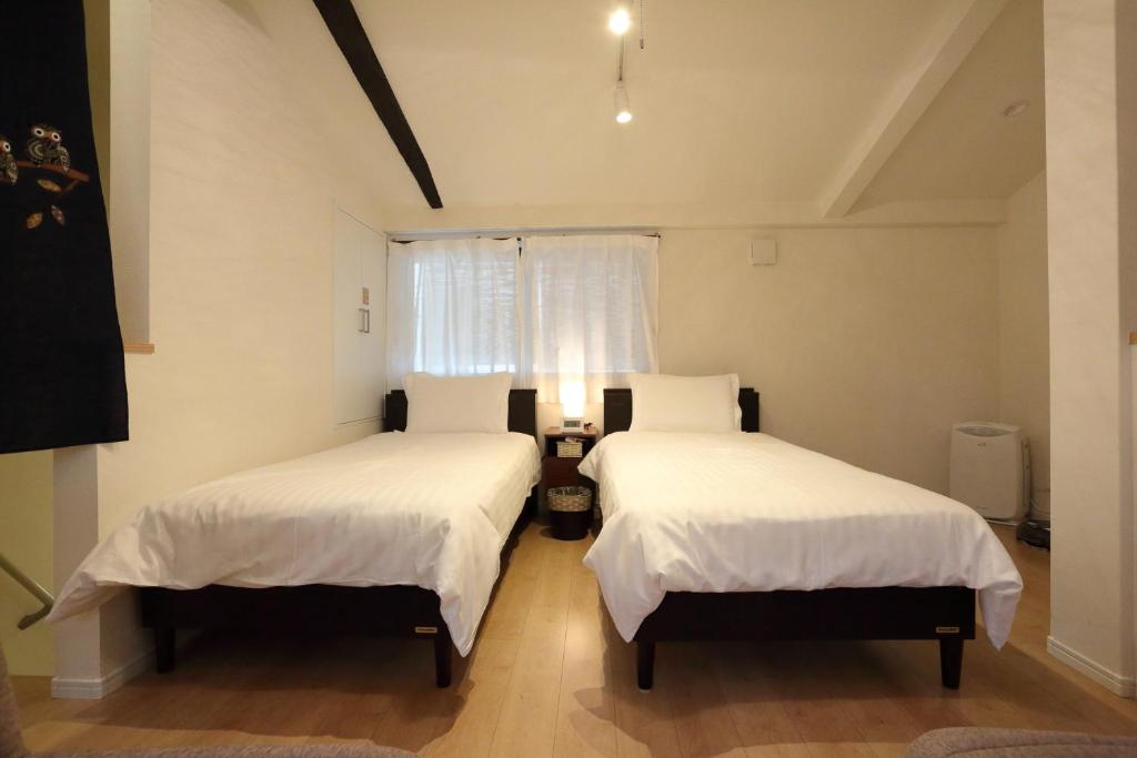 1 dormitorio con 2 camas y ventana en Kokon Higashiyama, en Kioto