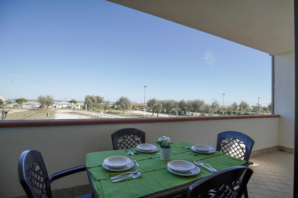 einen Tisch mit grüner Tischdecke und Stühlen sowie ein Fenster in der Unterkunft Residence Smith Sul Mare in Lido degli Estensi