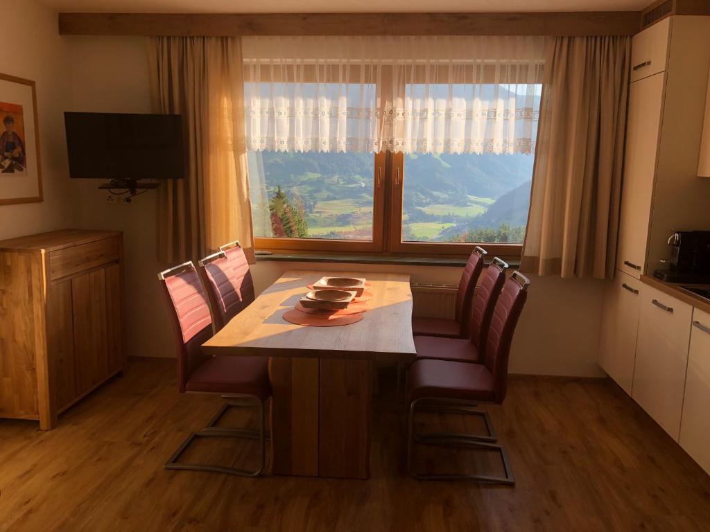 a dining room table with chairs and a large window at Sonnseitn Klaunz27 in Matrei in Osttirol