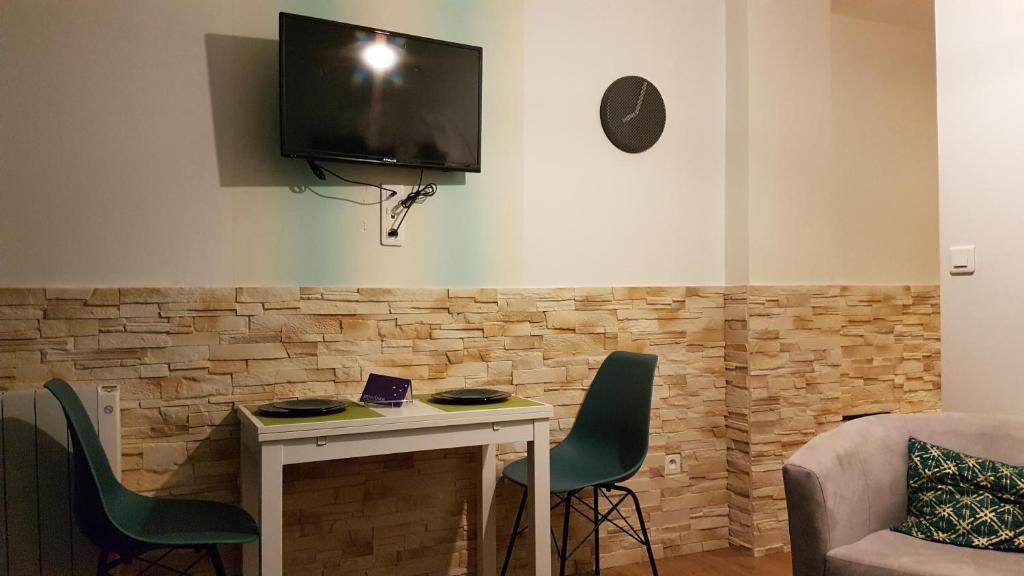 ein Wohnzimmer mit einem Tisch und einem TV an der Wand in der Unterkunft Studio Ramblas Centre Toulouse in Toulouse