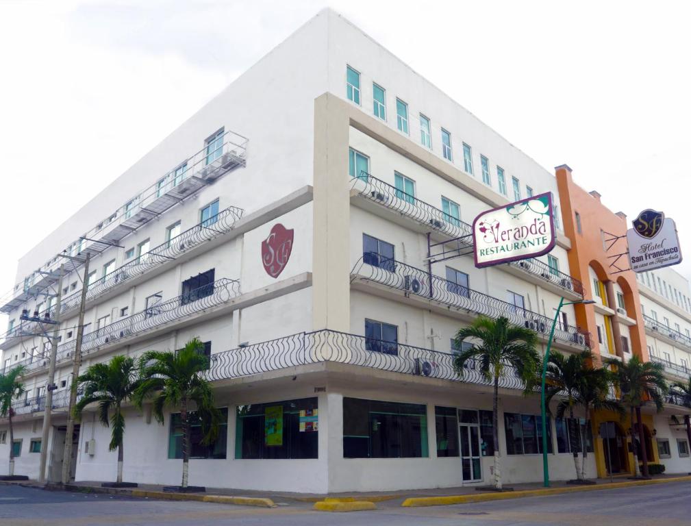 a large white building with palm trees in front of it at Hotel San Francisco in Tapachula