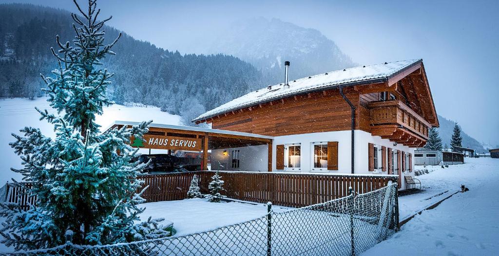 um edifício coberto de neve com uma árvore de Natal coberta de neve em Haus Servus em Klösterle