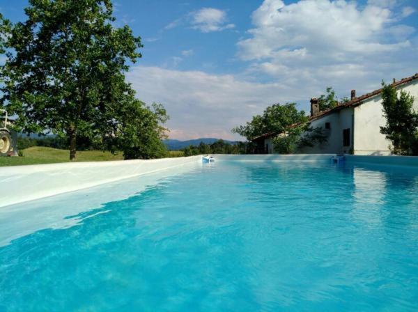 a large swimming pool with blue water in front of a house at Monte Termine Country House in Rioveggio