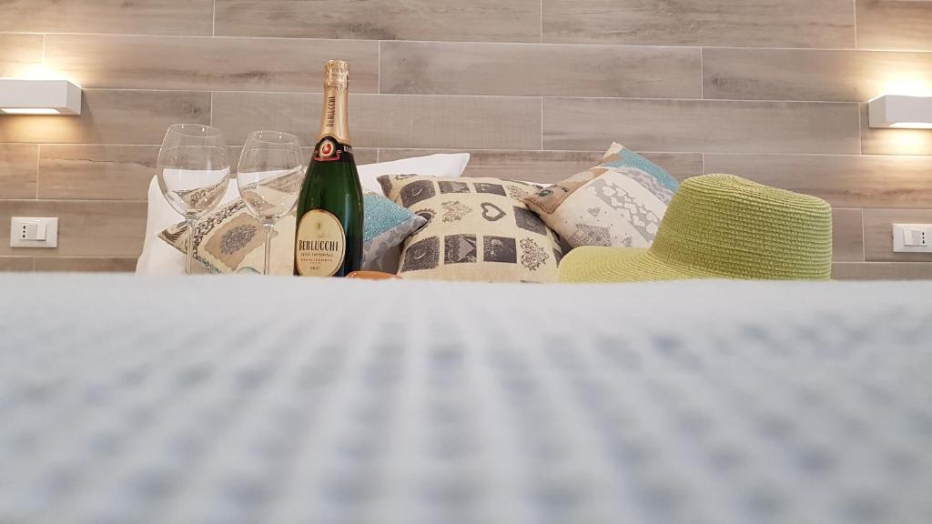 a bottle of wine sitting on a bed with pillows at Martin Holiday Apartments in Giardini Naxos